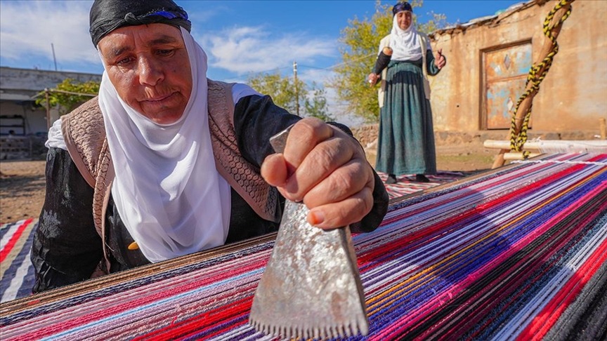 Evinin bahçesindeki tezgahta asırlık yöntemle kilim dokuyor