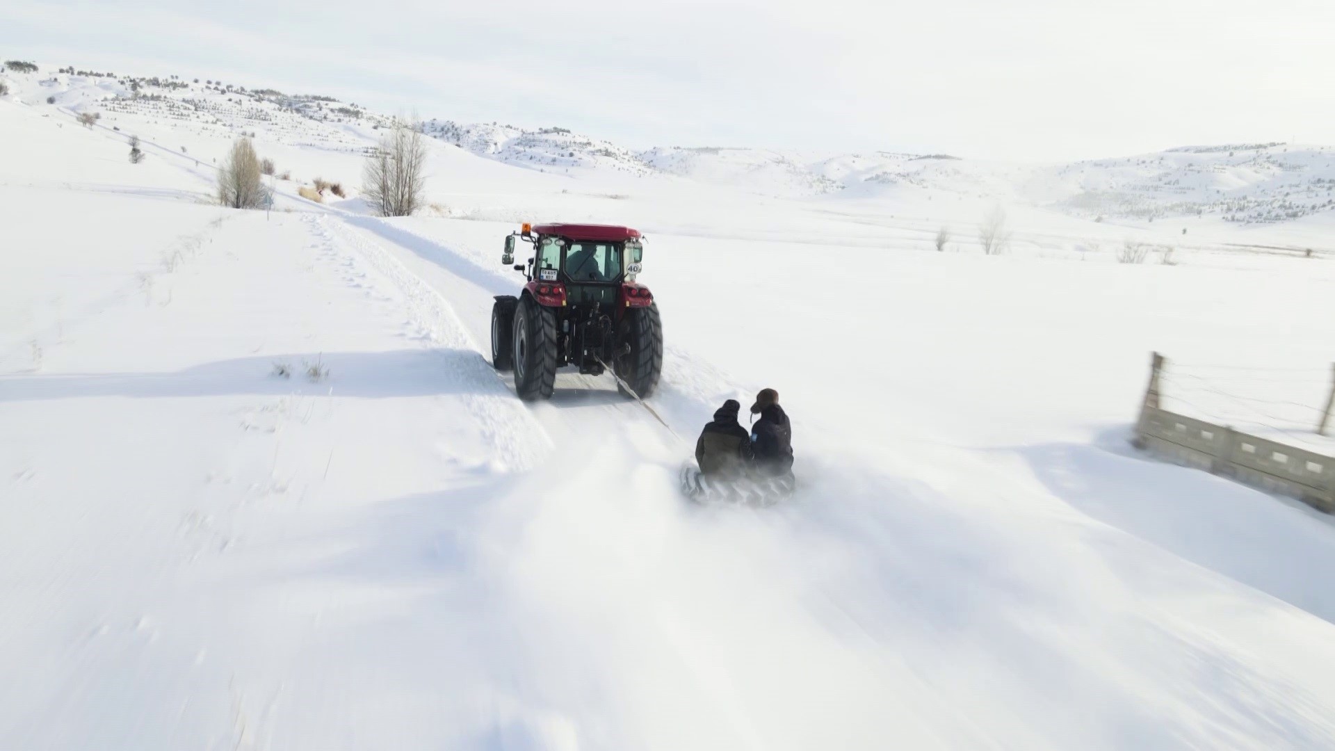 Kar yağışını fırsata çevirdiler, traktörün arkasında kayarak eğlendiler