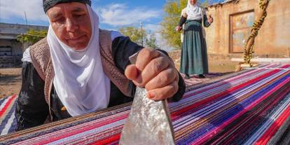 Evinin bahçesindeki tezgahta asırlık yöntemle kilim dokuyor